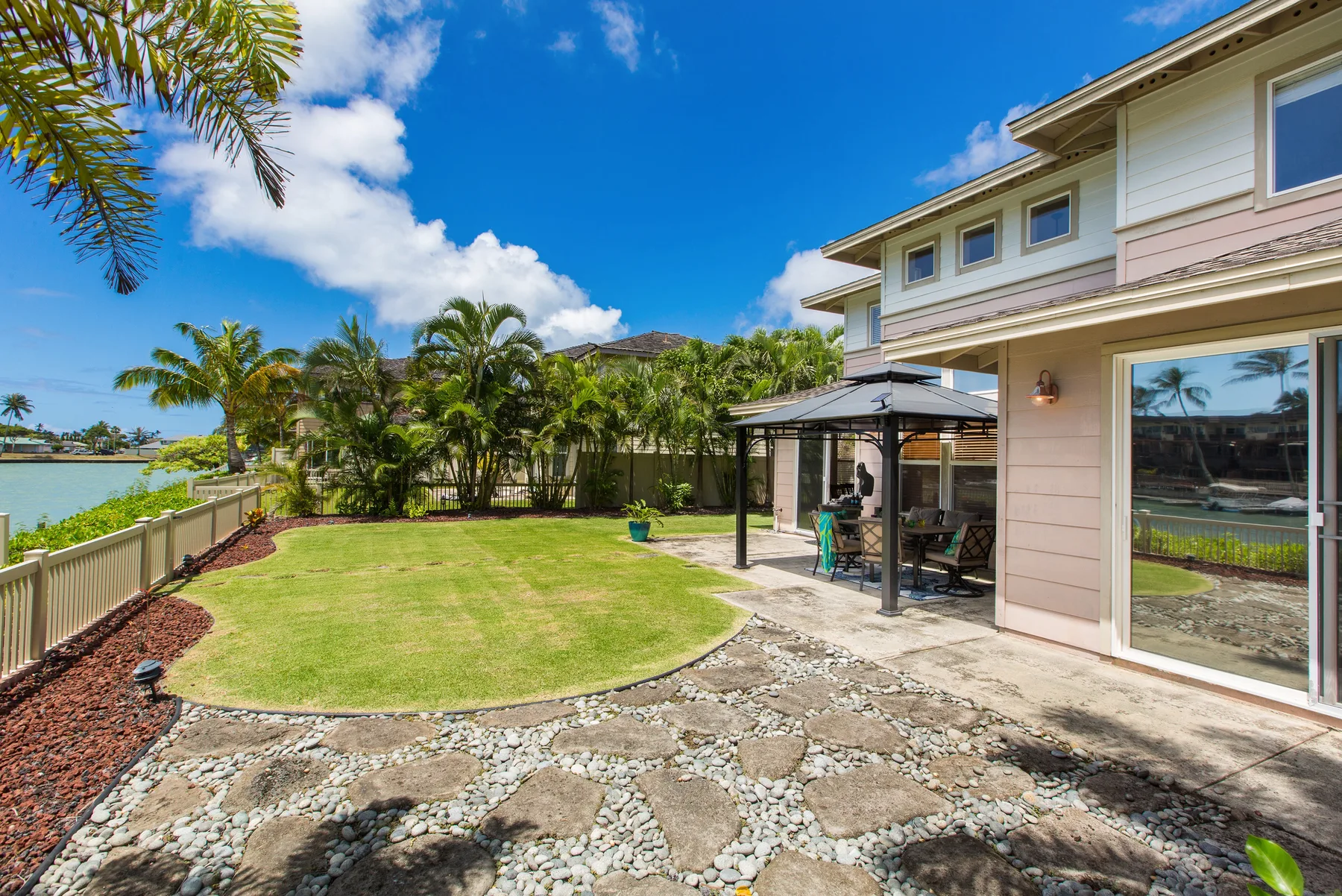 A landscaped backyard with a lawn, patio, and covered outdoor seating area.