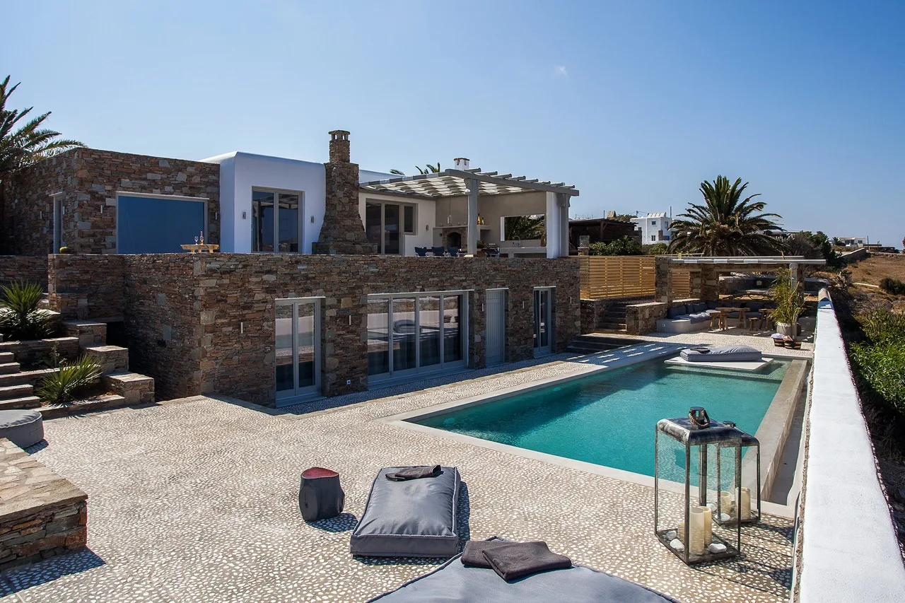 Una villa moderna con piscina y asientos al aire libre.
