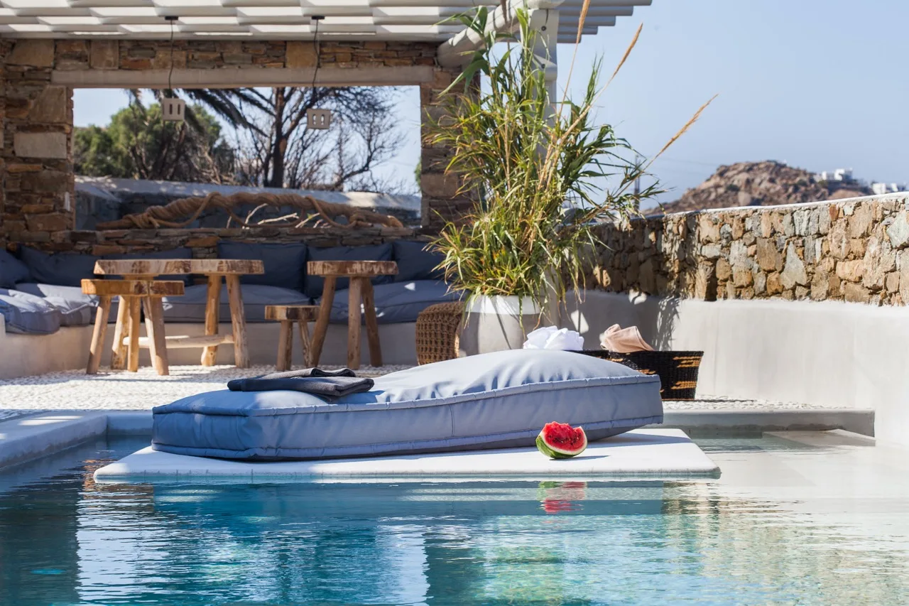 An outdoor pool with a floating cushion beside a shaded seating area.