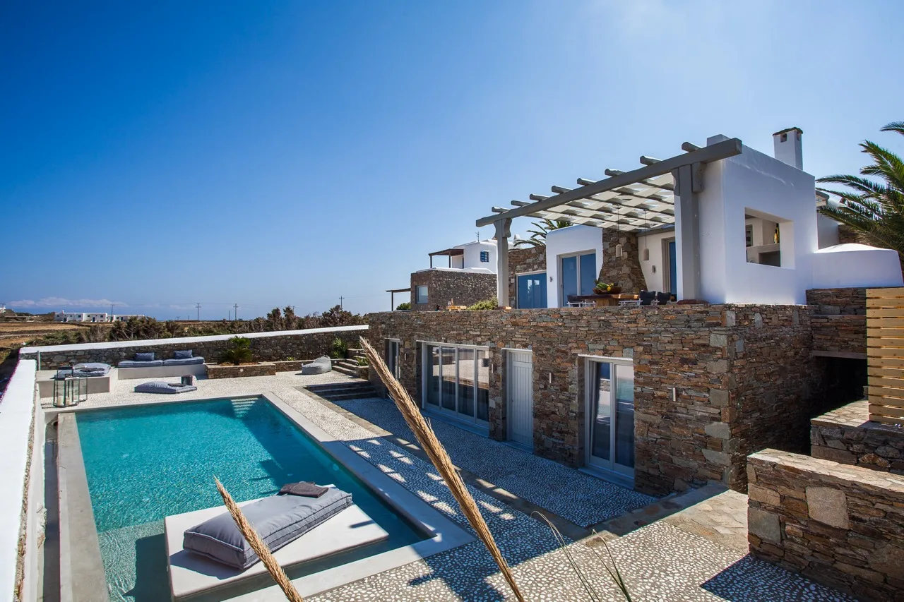 Una villa moderna con piscina y exterior revestido de piedra.