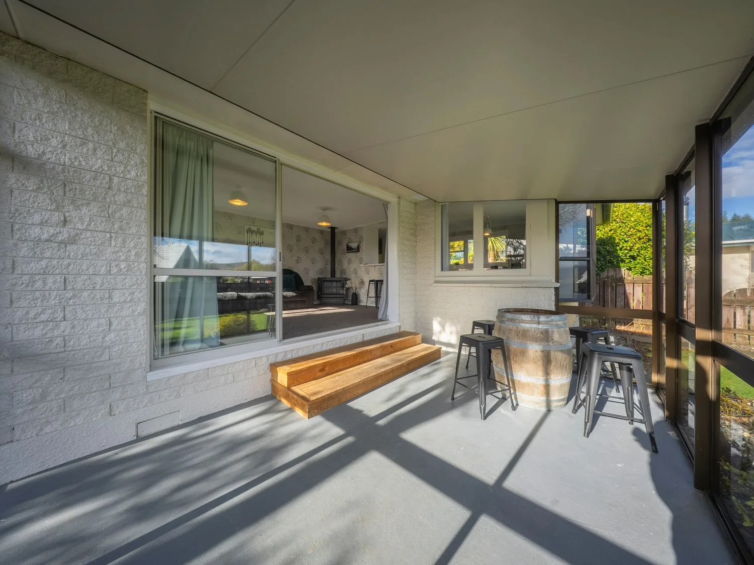 Un patio cubierto con un banco largo de madera y una mesa alta con taburetes.