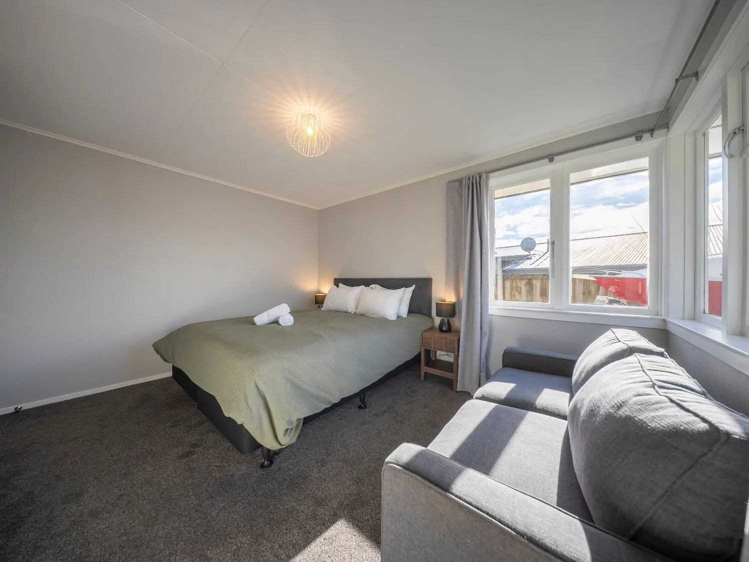 Un dormitorio con cama y sofá en Quiet on Quintin - Te Anau Holiday Home, Te Anau