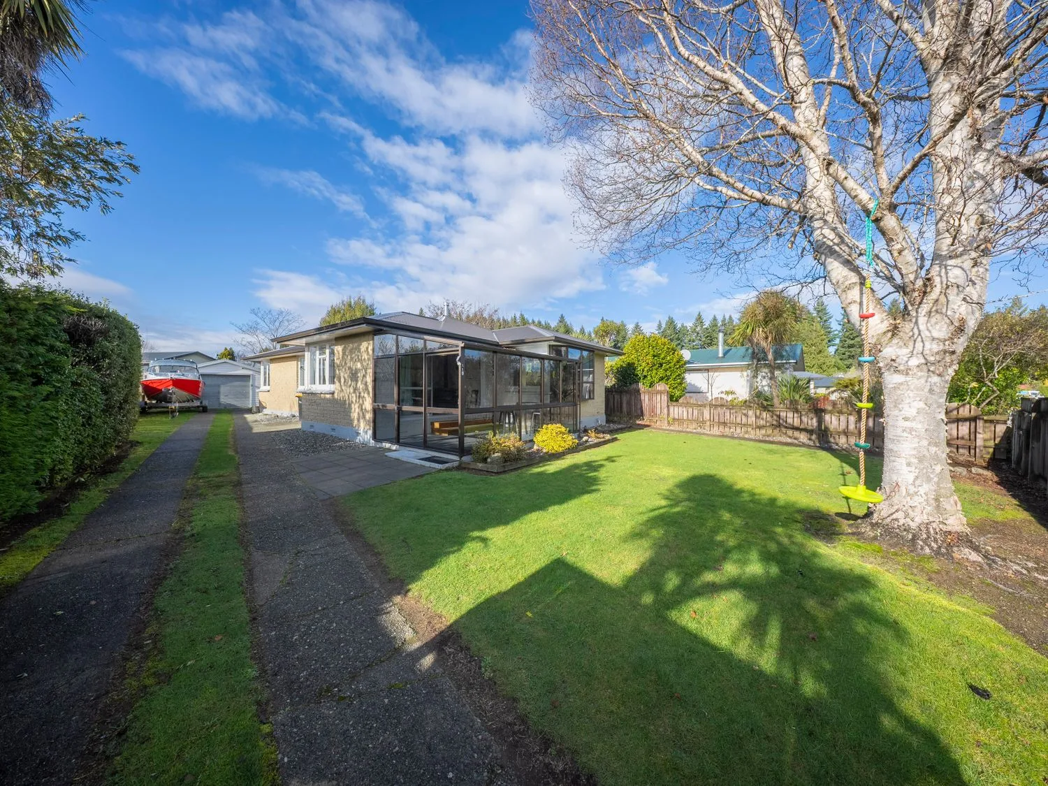 Una zona exterior con una casa, un patio y un árbol en Quiet on Quintin - Te Anau Holiday Home, en Te Anau