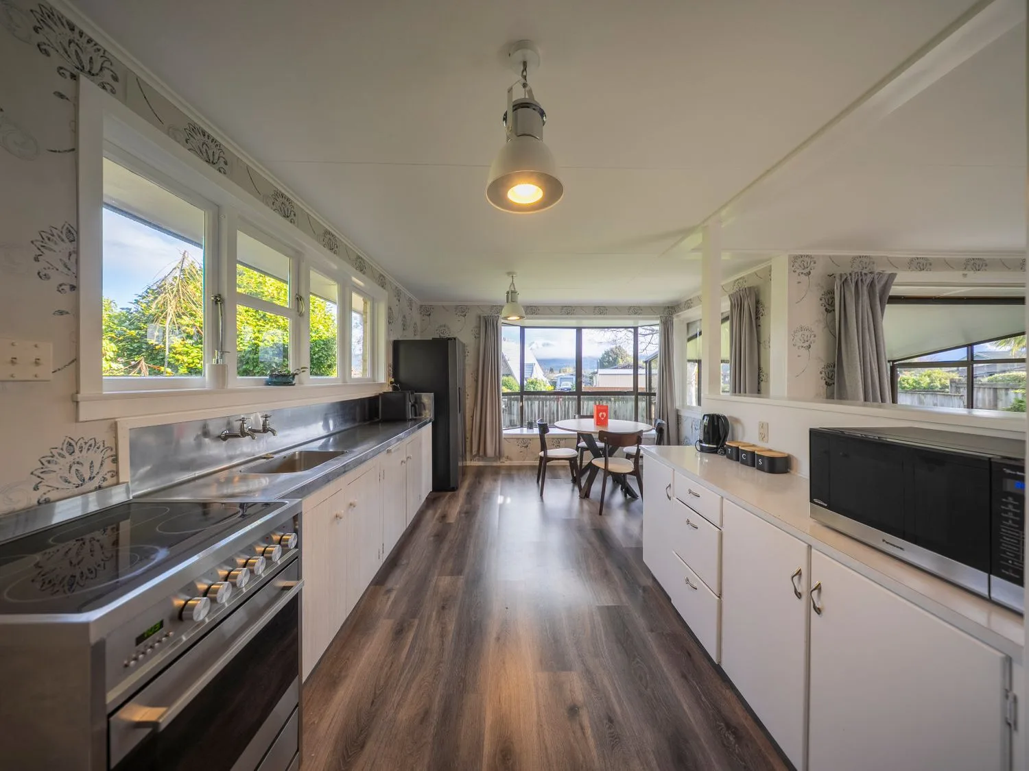 Una cocina con cocina de fogones, fregadero, refrigerador y mesa de comedor en Quiet on Quintin - Te Anau Holiday Home, Te Anau