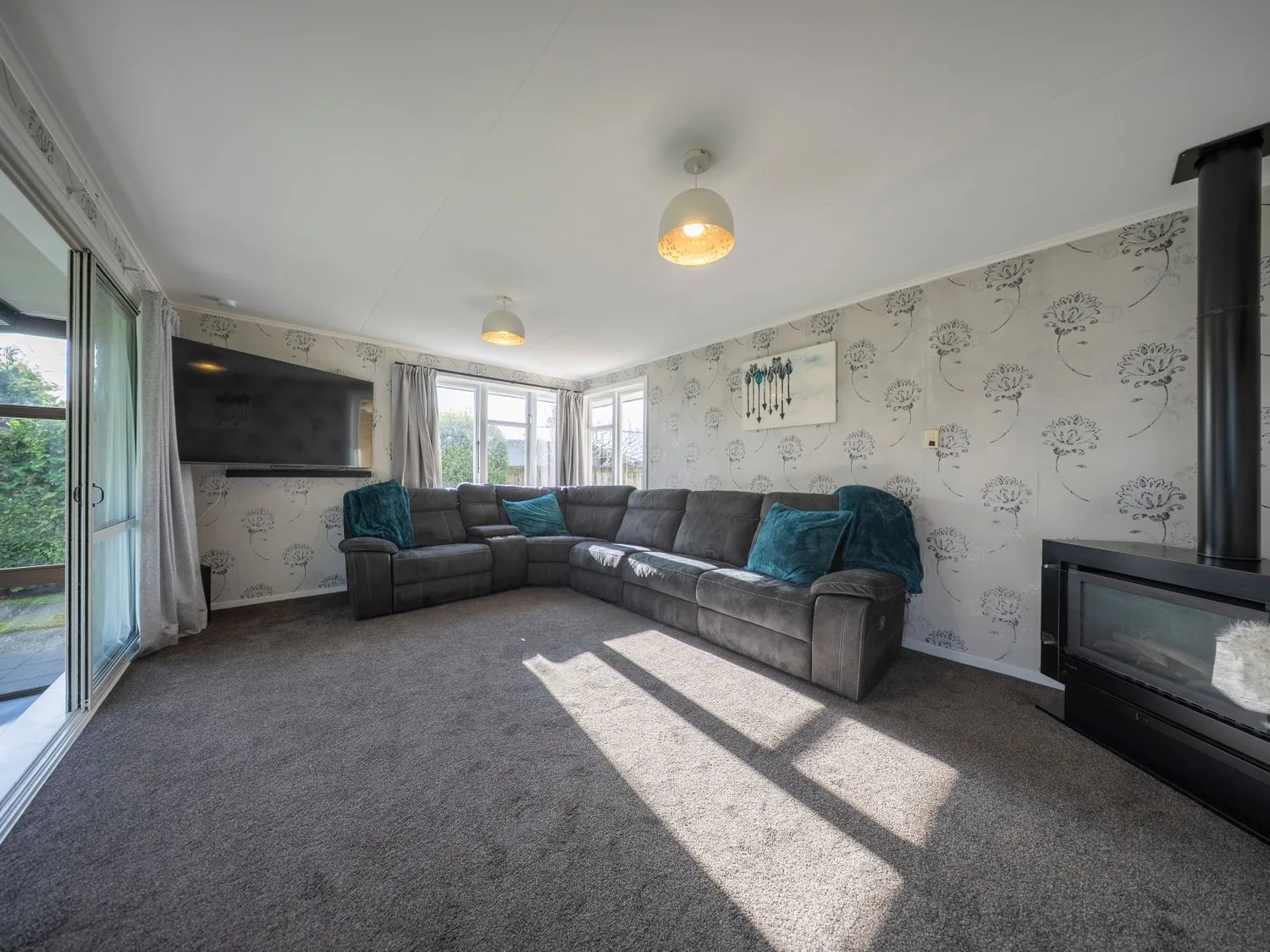 Una sala de estar con sofá y televisor en Quiet on Quintin - Te Anau Holiday Home, Te Anau