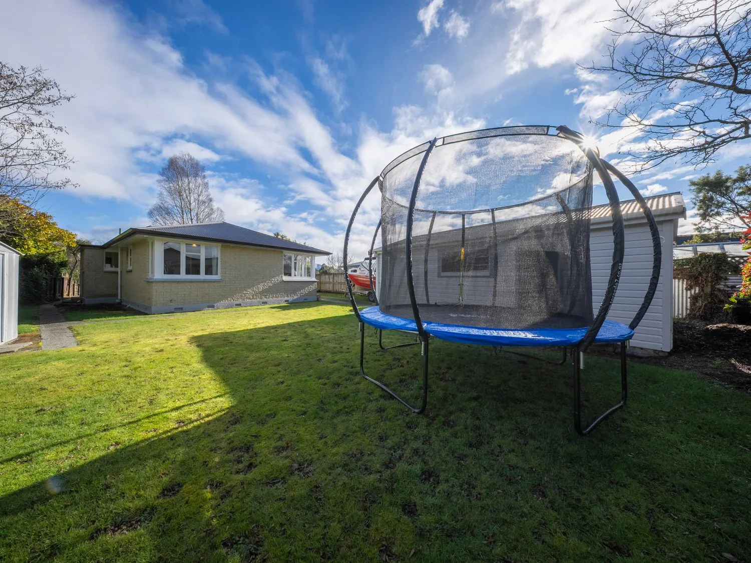 Un jardín con una cama elástica y una casa en Quiet on Quintin - Te Anau Holiday Home, en Te Anau
