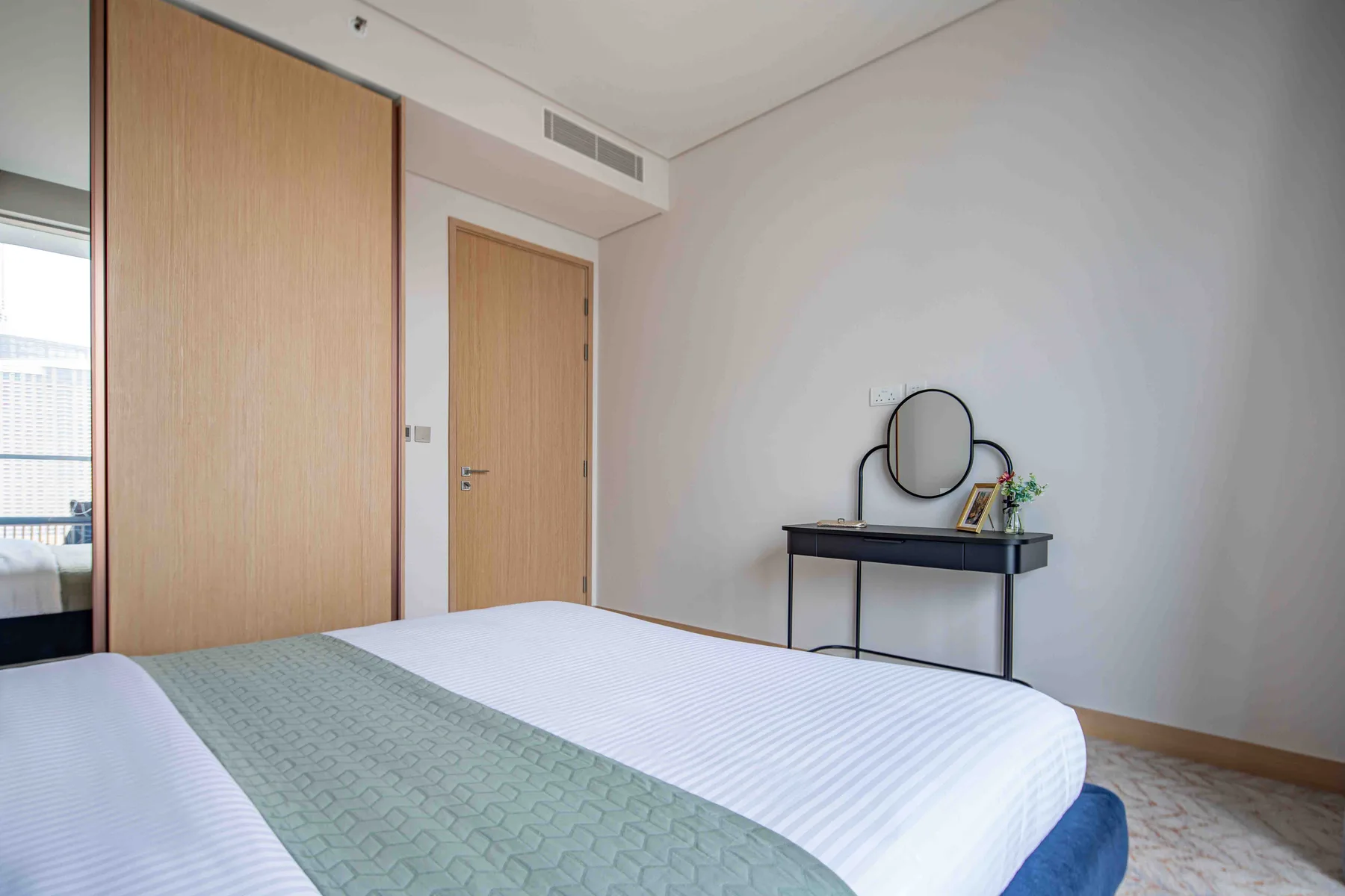 Un dormitorio con una cama y un escritorio pequeño con un espejo redondo.