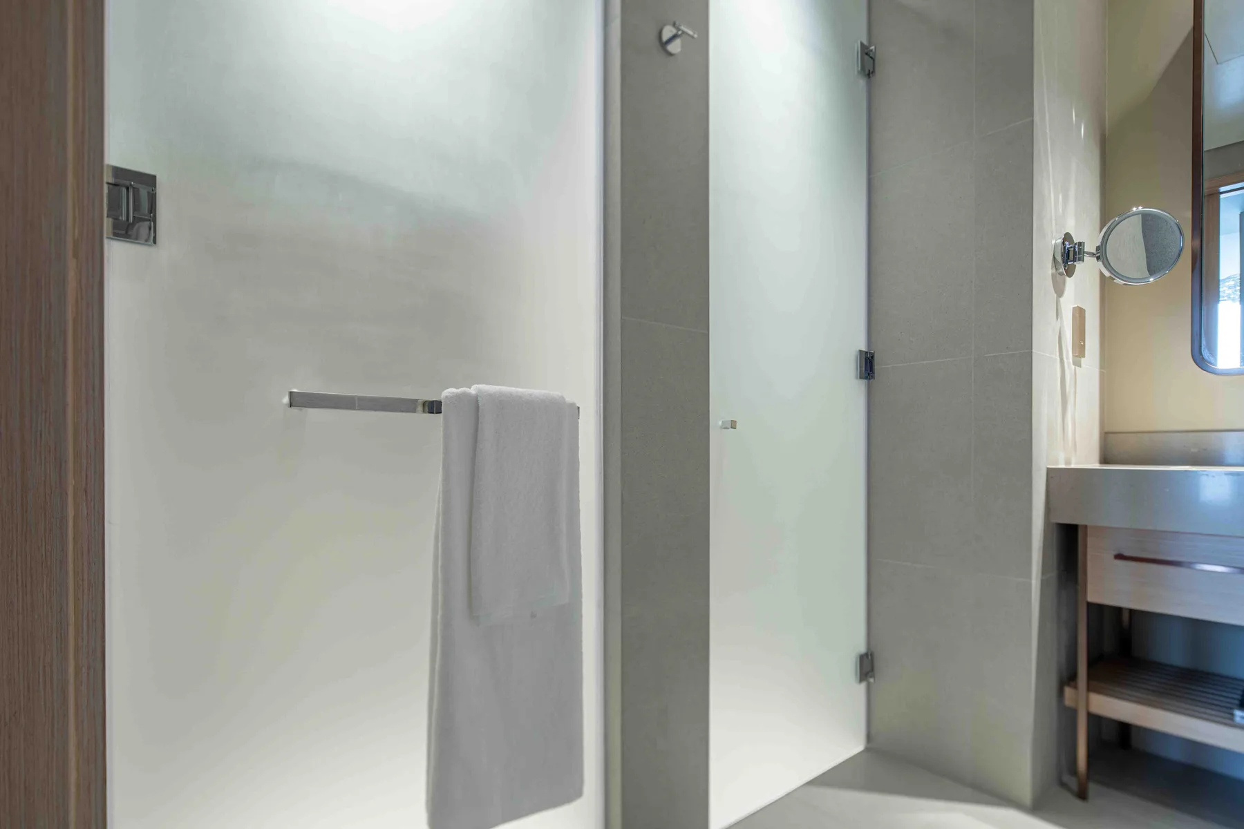Un baño con azulejos, una ducha de vidrio y una toalla colgada en una barra.