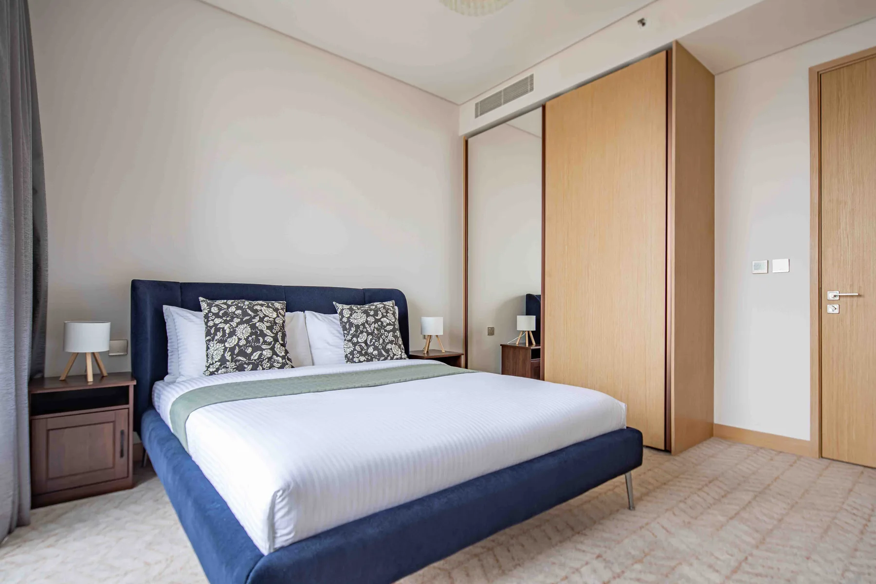 Un dormitorio con una cama, mesitas de noche y un armario con paneles de madera.
