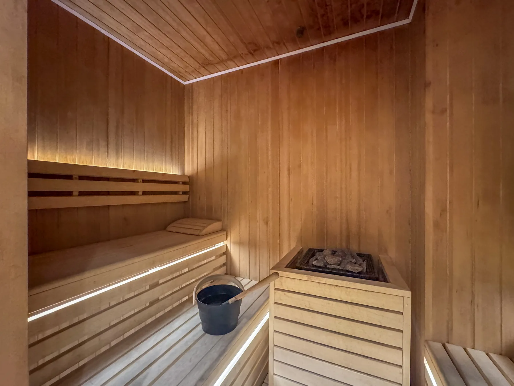 Una sauna revestida de madera, con asientos escalonados y una estufa de piedras.