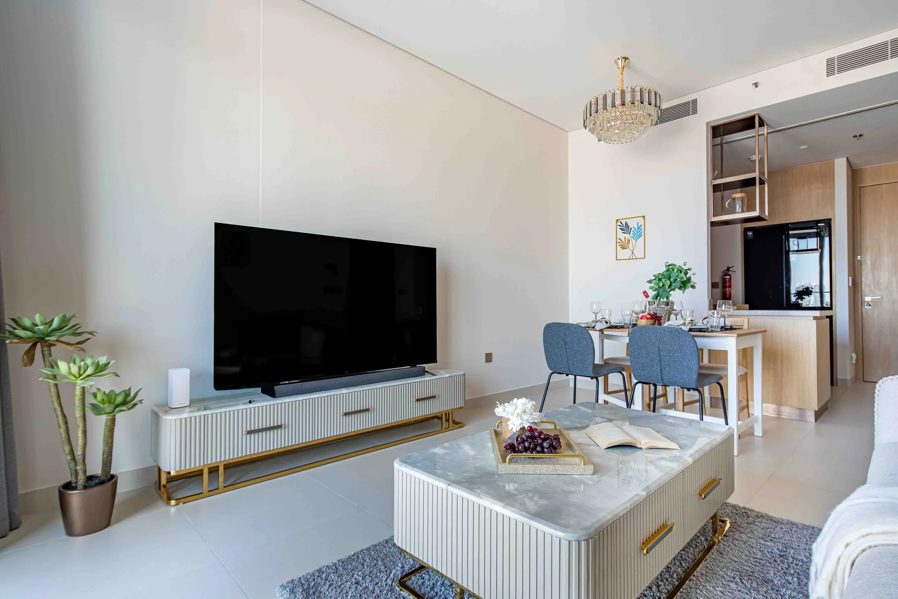 Una luminosa sala de estar y comedor con un televisor y una mesa preparada para comer.
