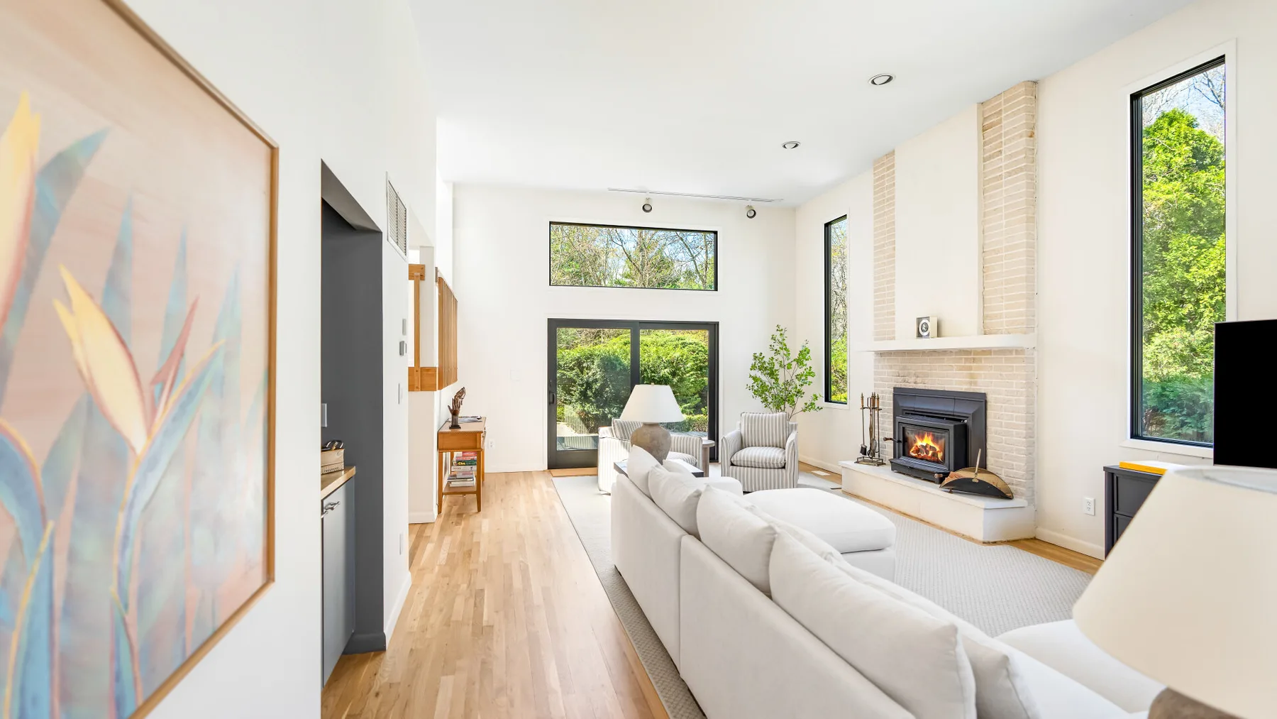 Una sala luminosa con asientos claros y una chimenea junto a ventanas altas.