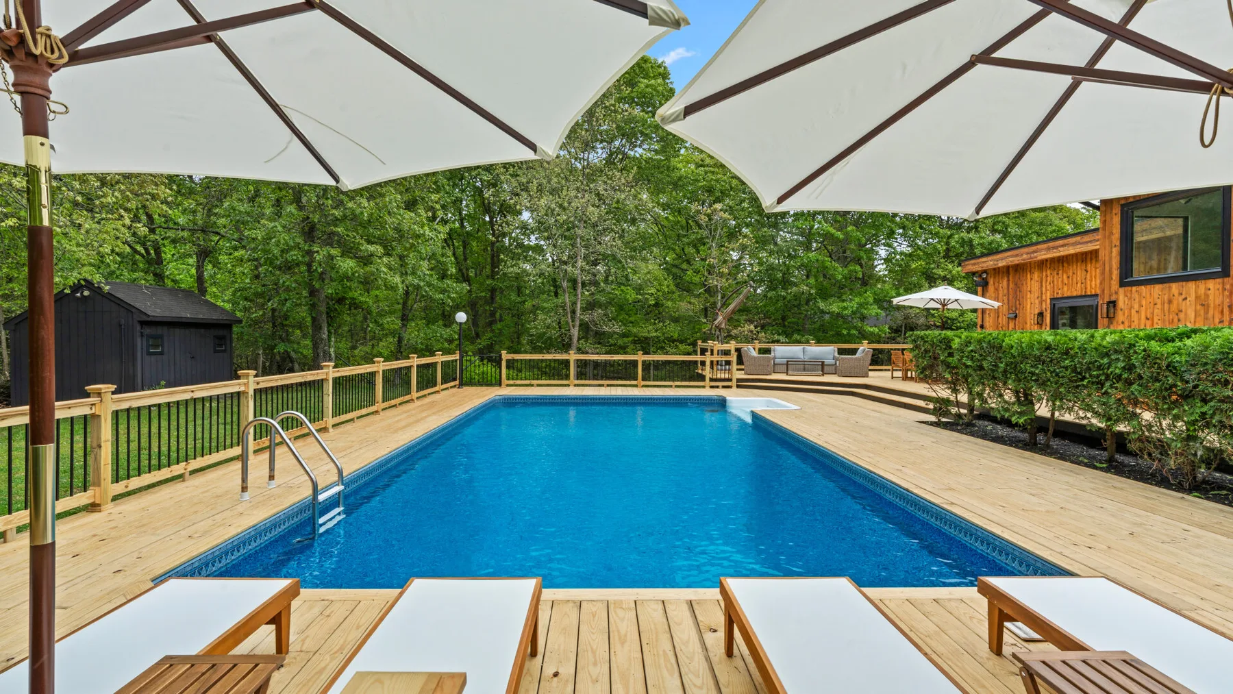 Una piscina al aire libre está rodeada por una terraza de madera y asientos.