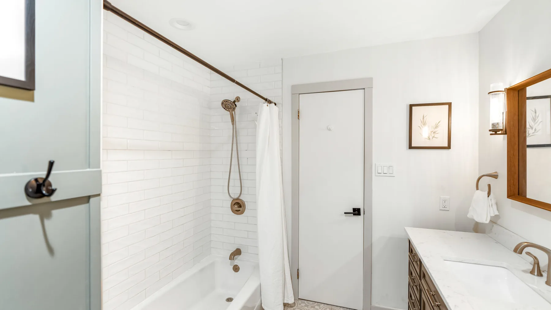 Un baño luminoso con una ducha de azulejos y un tocador largo.