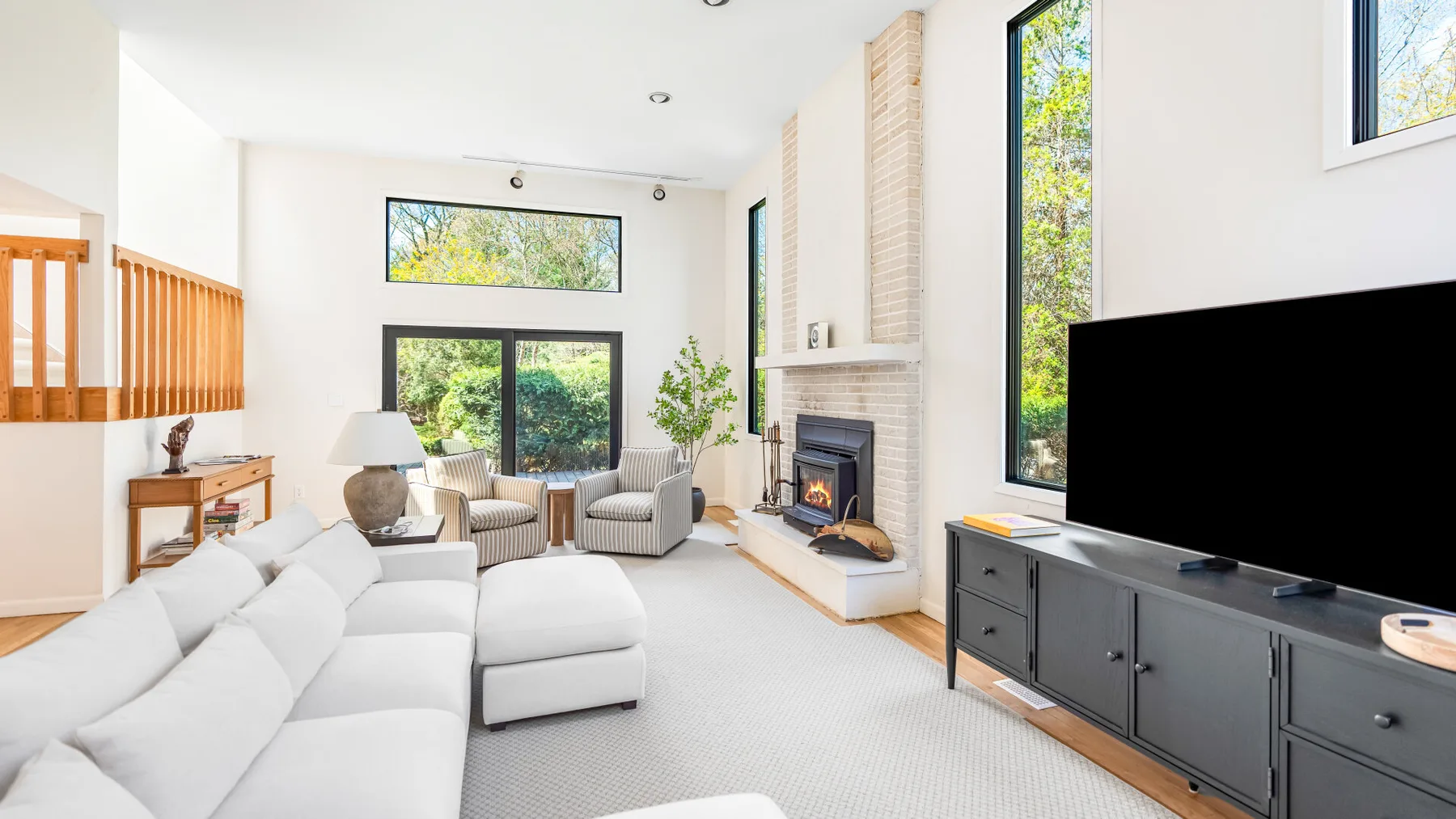 Una sala de estar luminosa con asientos, una chimenea y grandes ventanas.