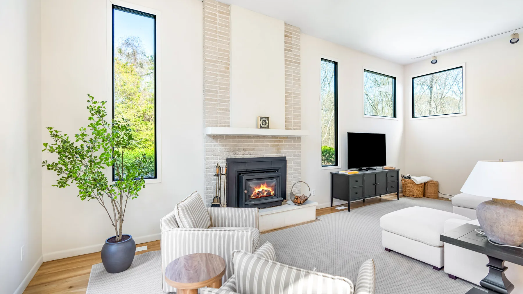 Una sala de estar luminosa con chimenea, televisor y asientos.