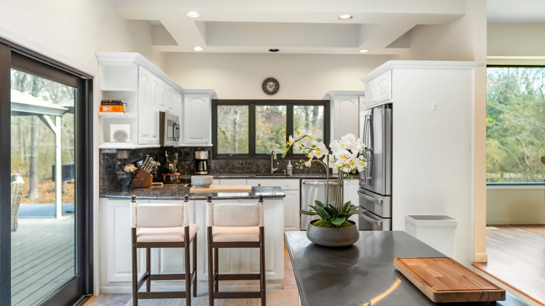 Una cocina luminosa con isla central, asientos altos y ventanas amplias.