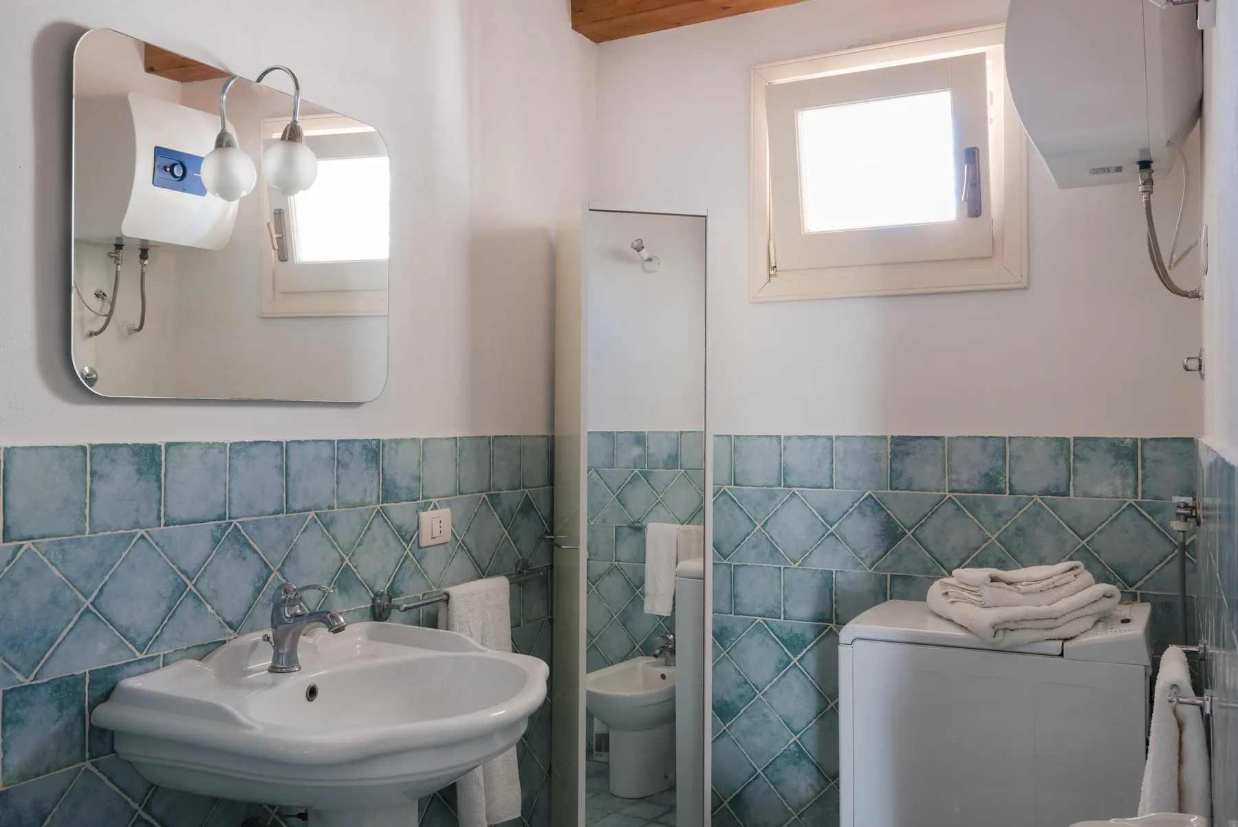 A bathroom with a sink, tiled walls, and a washing machine.