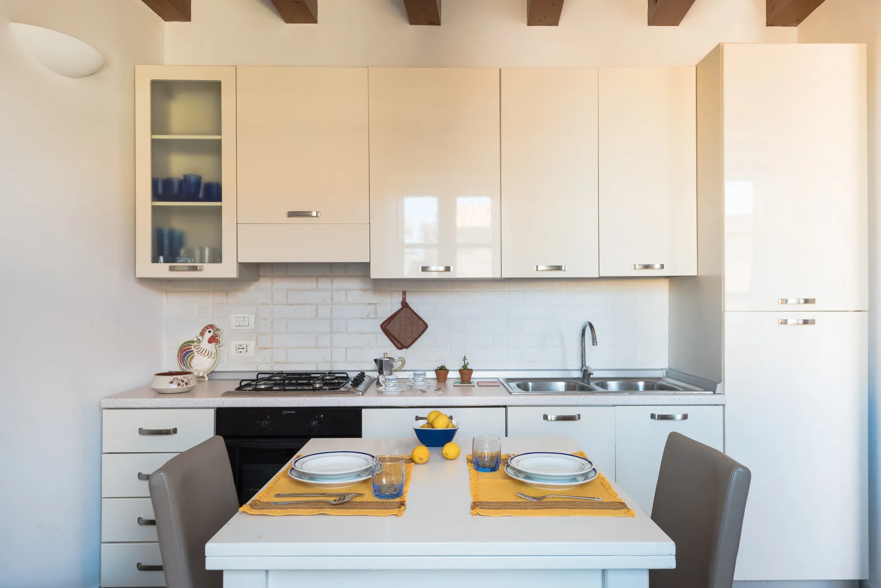 A bright kitchen with a dining table set with plates and glasses.