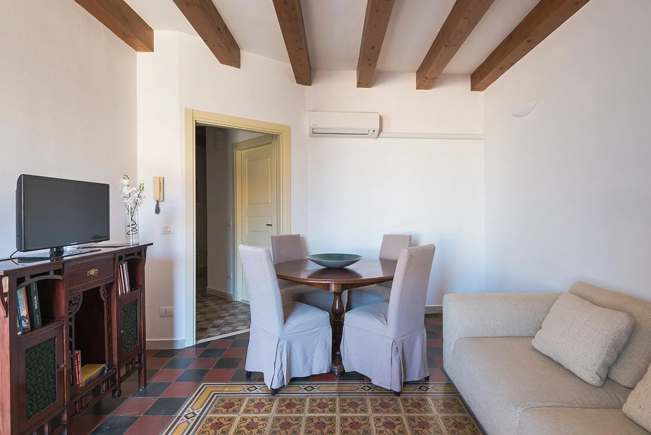 A bright living and dining room with a table, seating, and a television.