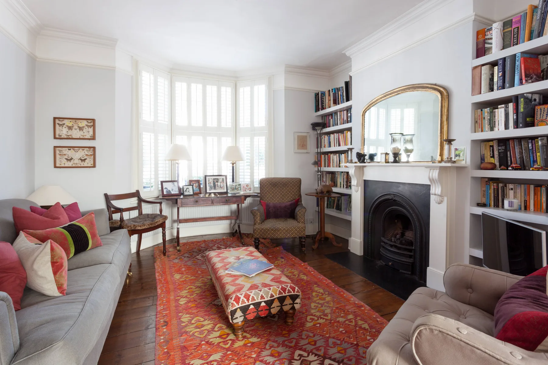 A bright living room with seating, a fireplace, and a patterned rug.