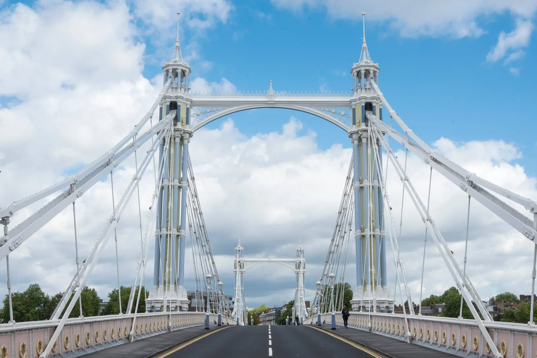 A suspension bridge stretches across the road beneath a partly cloudy sky.
