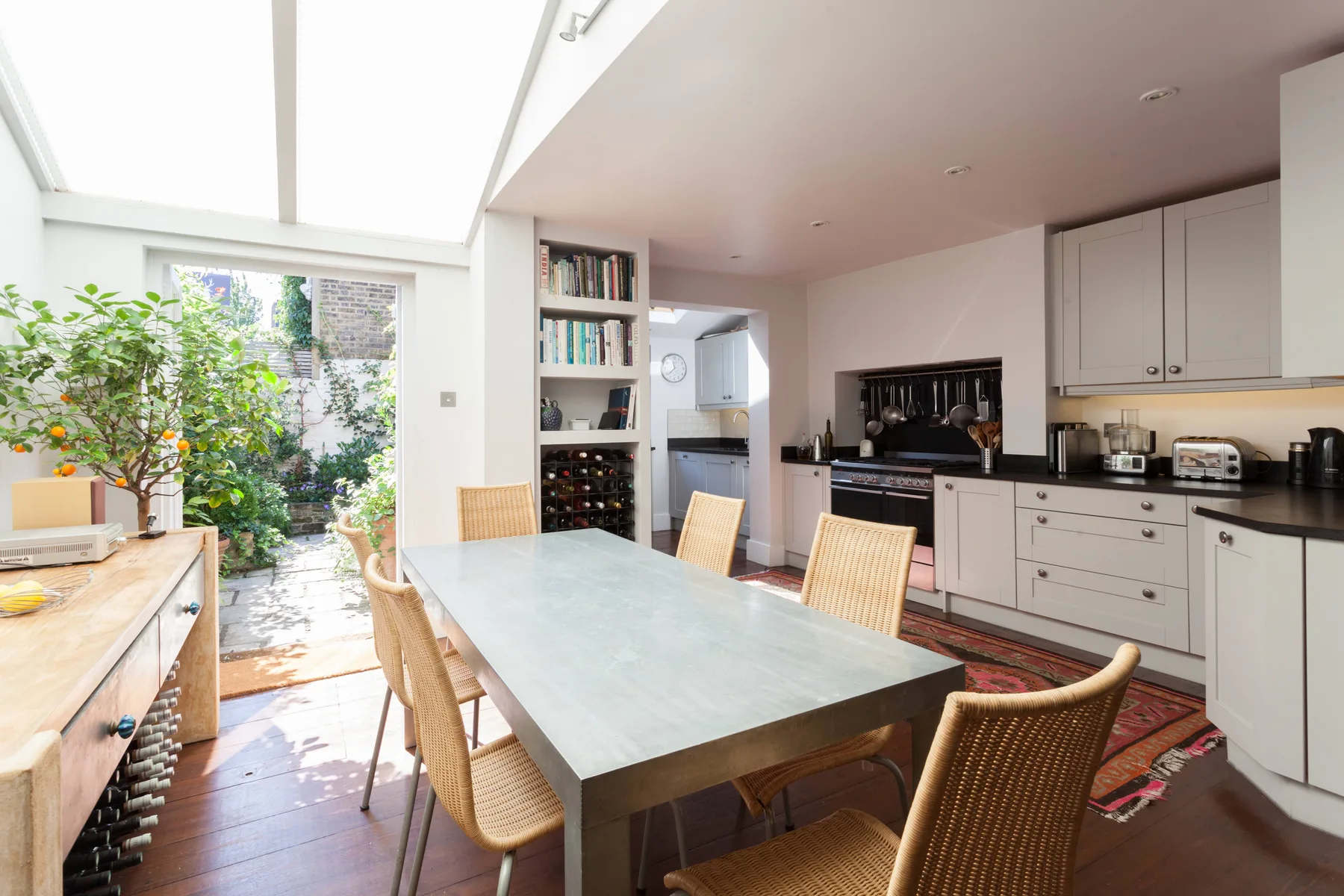 A bright kitchen and dining area with a long table beside a glass garden door.