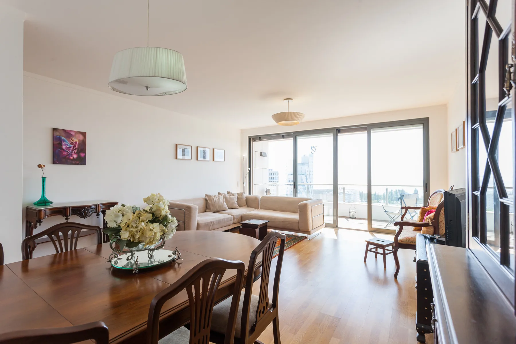 A bright living and dining area with seating beside large windows.