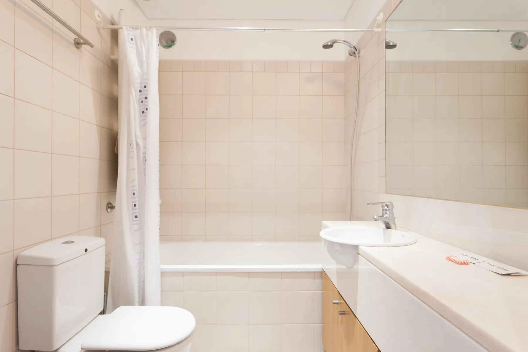 A tiled bathroom with a bathtub, shower curtain, toilet, and sink.