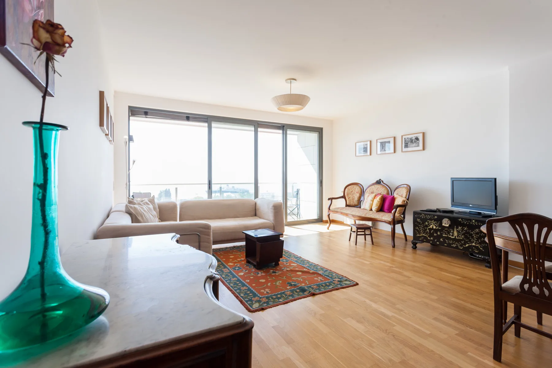 A bright living room with seating, a rug, and large windows.