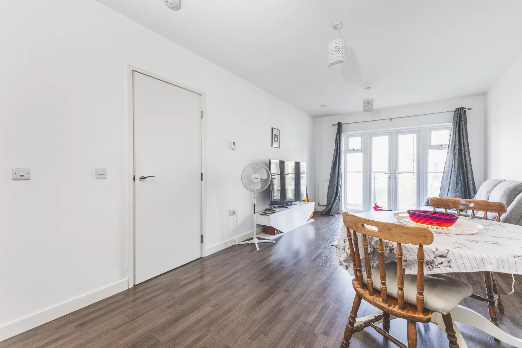 A bright dining area with a long table and windows across the far wall.