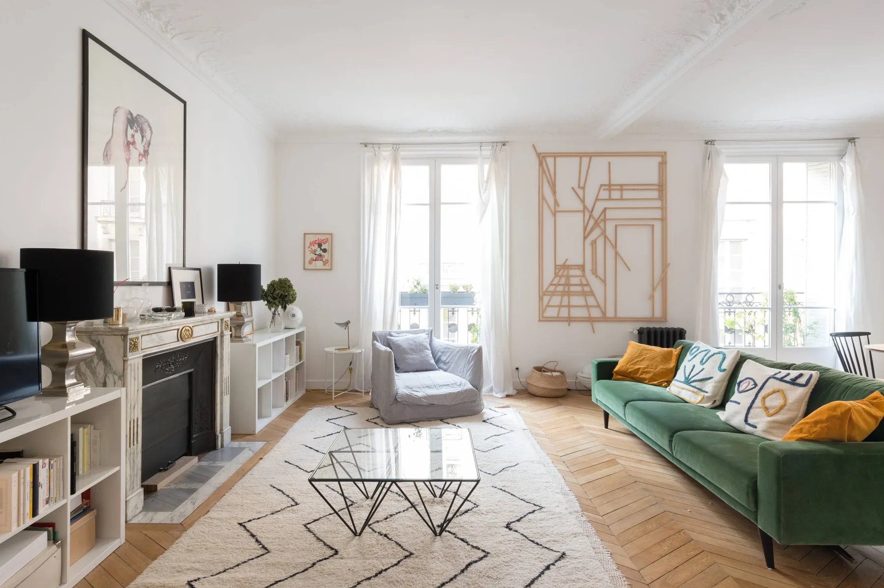 A bright living room with a green seating area and a glass coffee table.