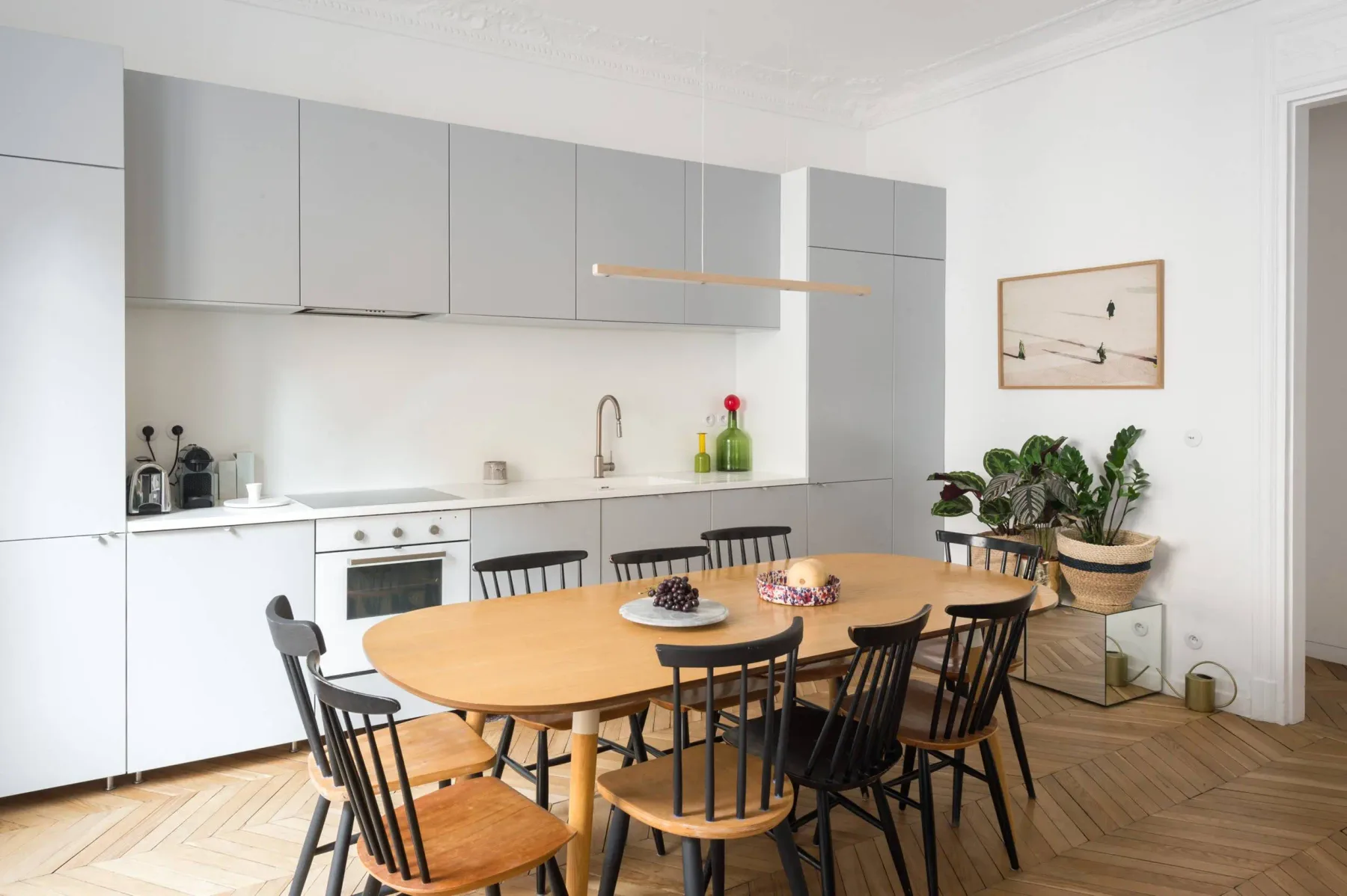 A dining area with a wooden table beside a bright kitchen.