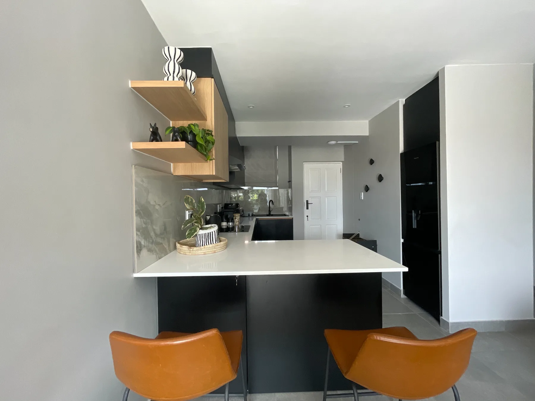 A modern kitchen with a counter and orange seating.