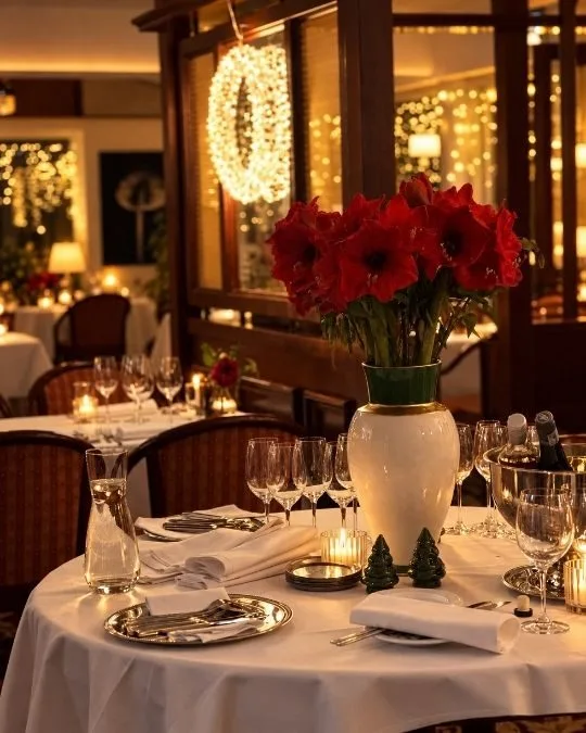 Comedor del restaurante con mesas puestas, velas y flores rojas.