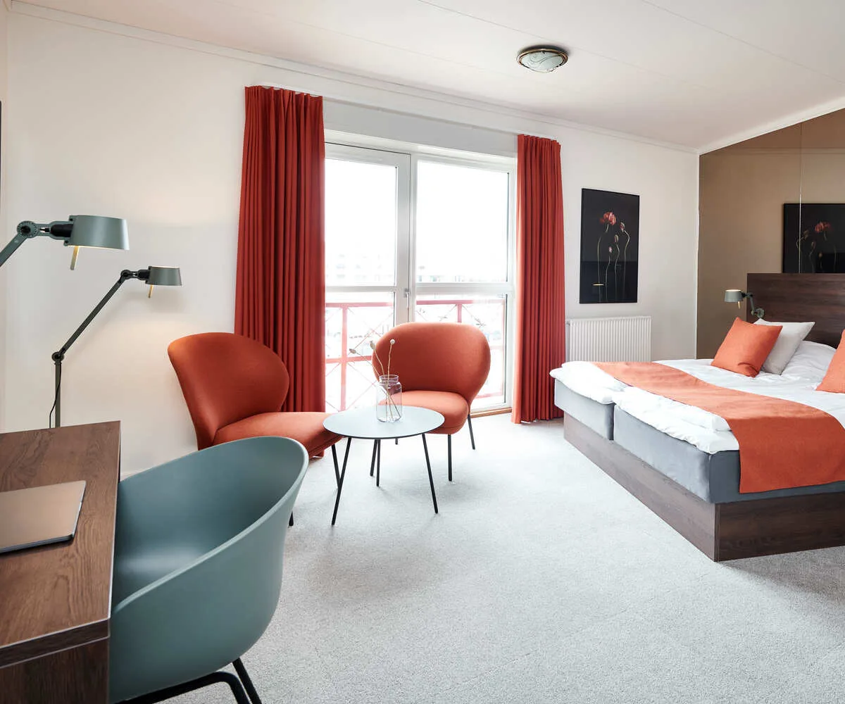 Habitación luminosa y moderna con una cama doble y zona de estar.