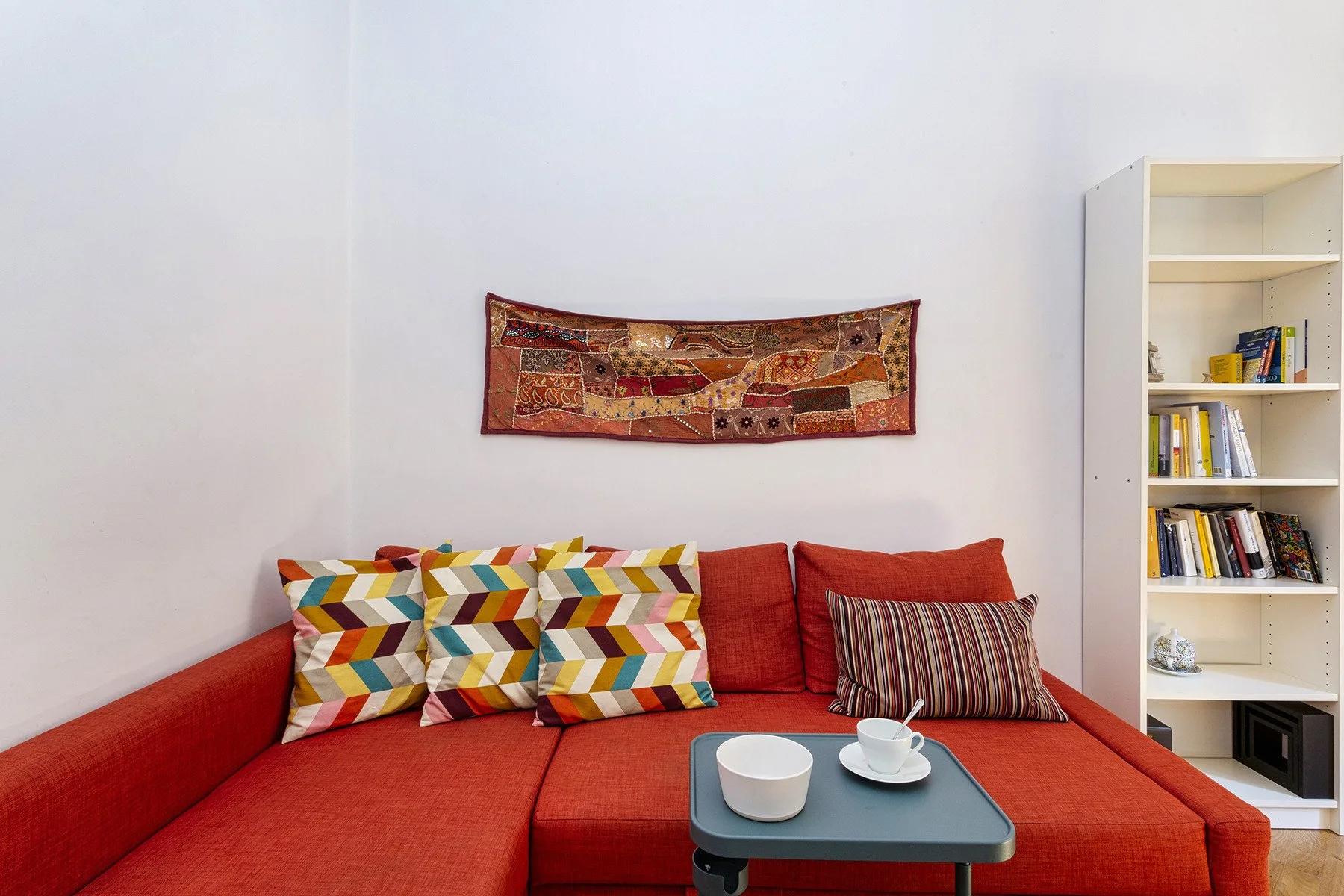 Una sala de estar con asientos rojos, cojines estampados y una pequeña mesa de centro.