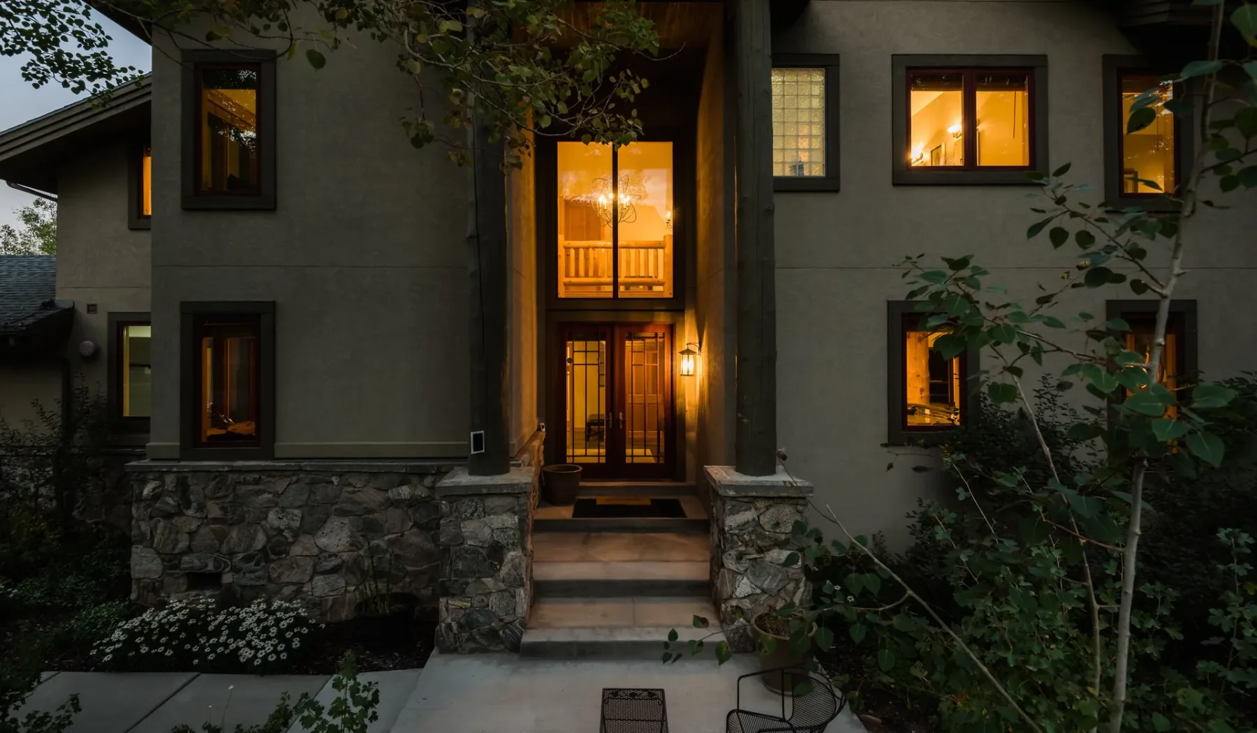 Exterior de un edificio de dos pisos con entrada y ventanas iluminadas al anochecer.