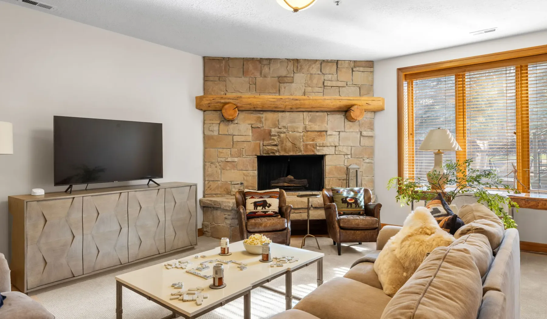 Sala de estar con chimenea de piedra, televisor y asientos alrededor de una mesa de centro.
