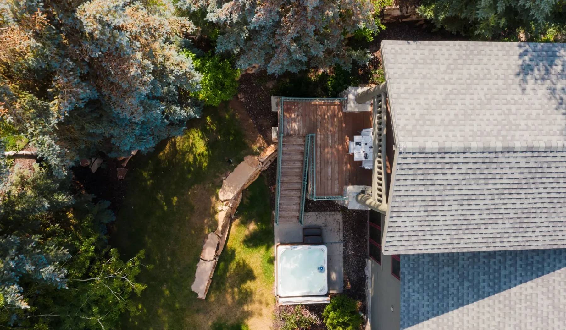 Vista aérea de una casa junto a un jardín arbolado y un pequeño patio exterior.