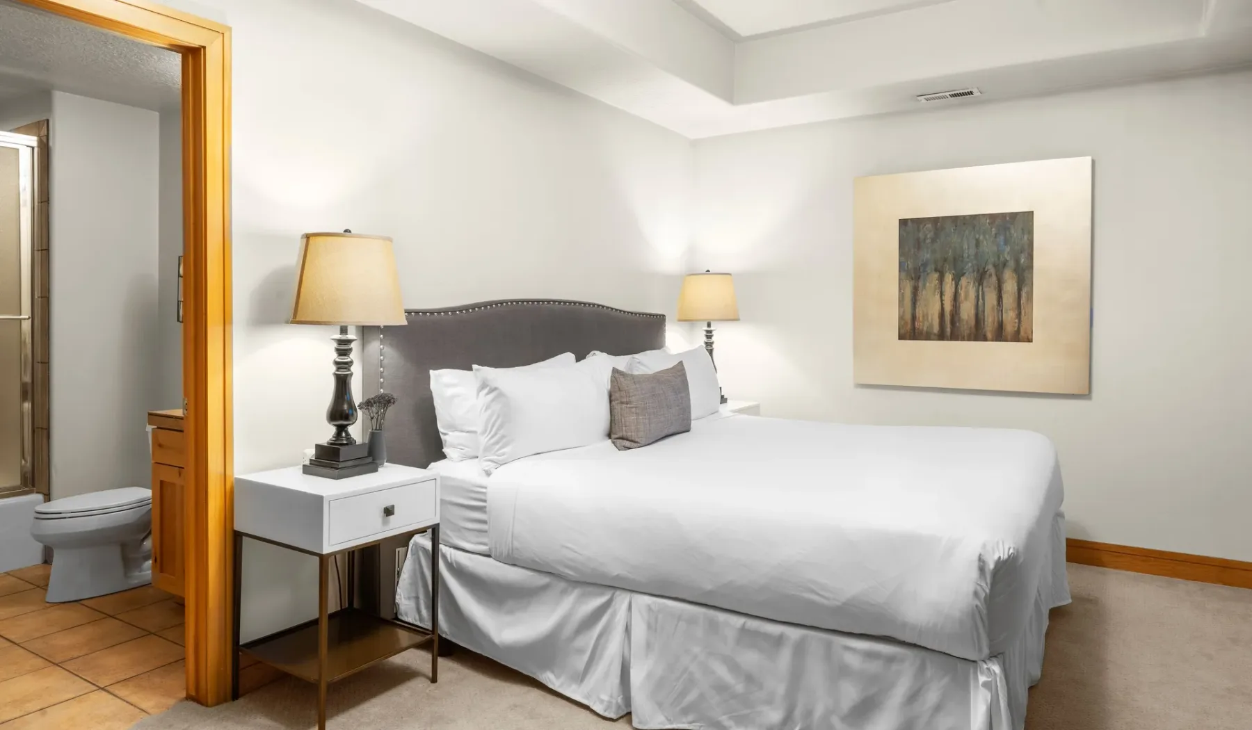 Un dormitorio con una cama grande, mesitas de noche y un cuadro enmarcado.