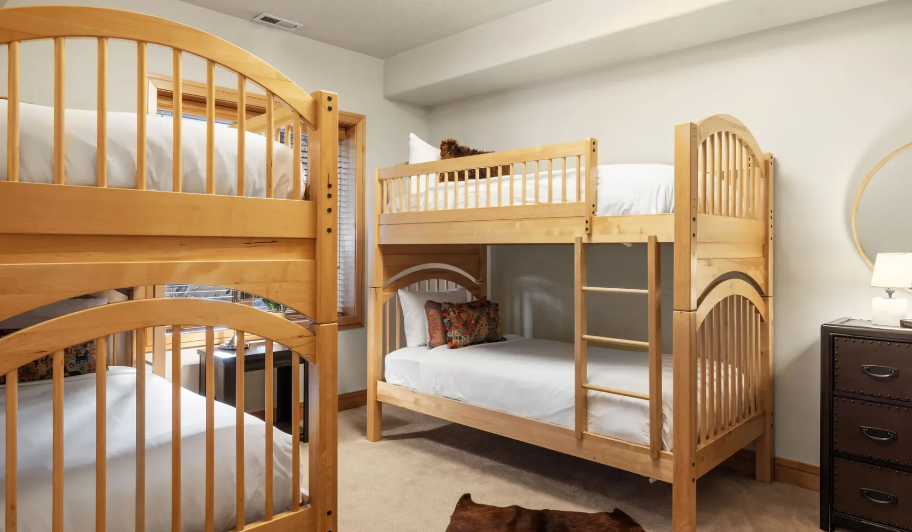 Un dormitorio con literas de madera y ropa de cama blanca.