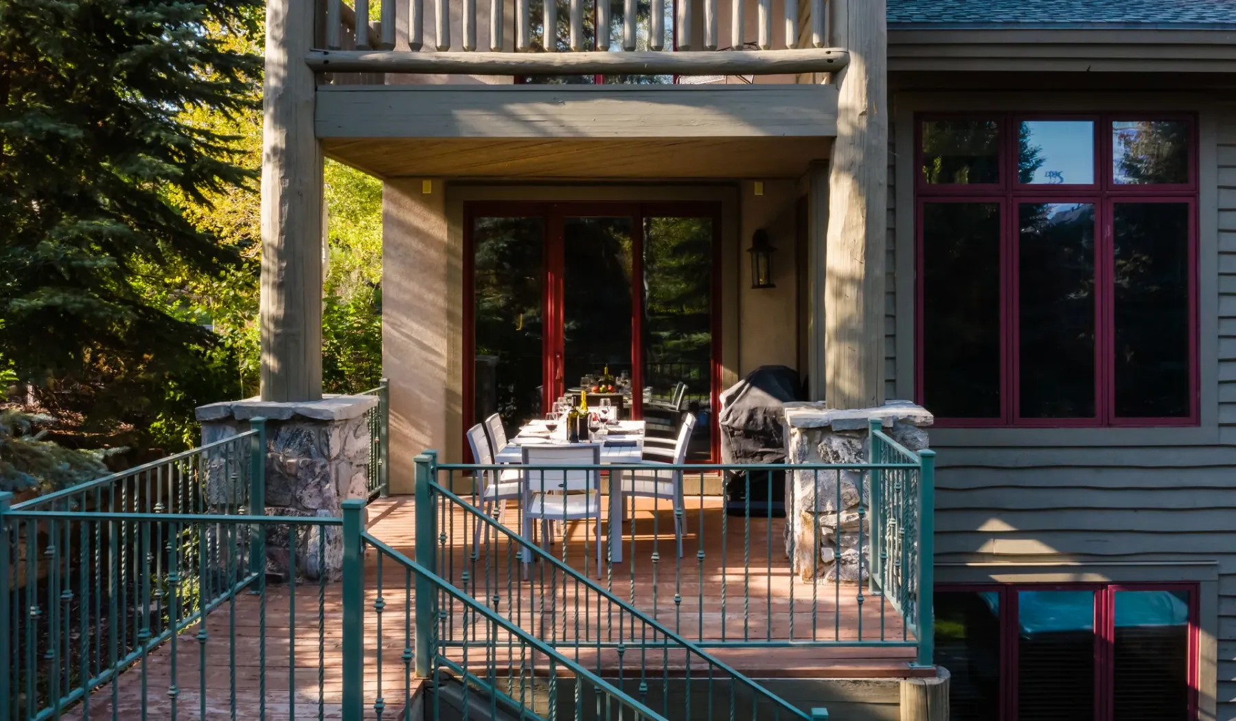 Un patio exterior con una mesa de comedor y sillas junto a grandes ventanas.
