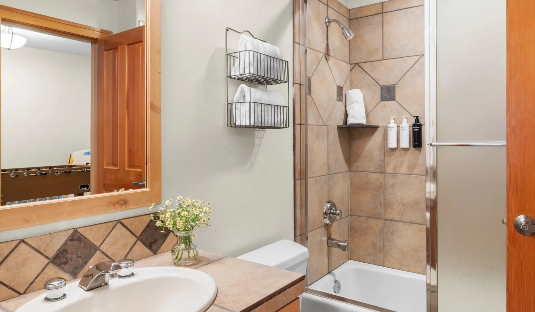 Un baño con lavabo, ducha de azulejos y espejo con marco de madera.