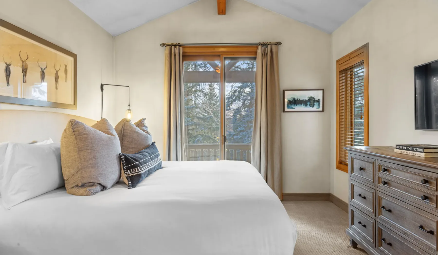 Un dormitorio con cama, ventana con cortinas y cómoda.