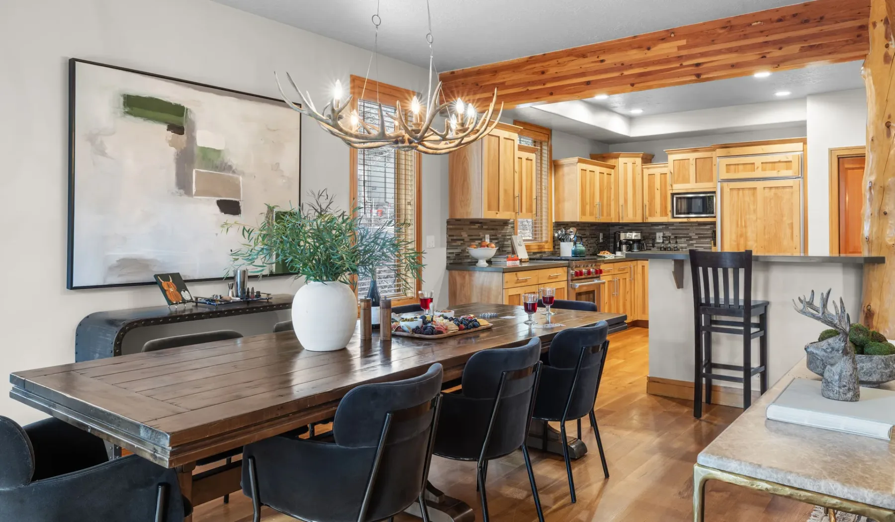Comedor abierto con una mesa larga junto a una cocina con gabinetes de madera.