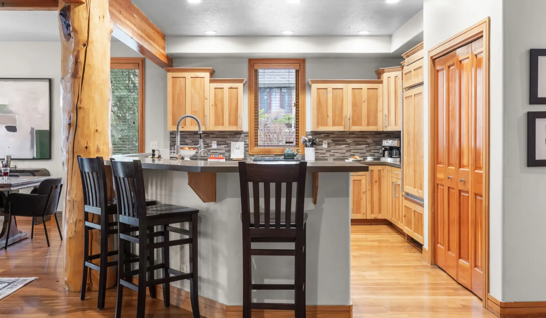 Una cocina con una isla central, gabinetes de madera y asientos altos.