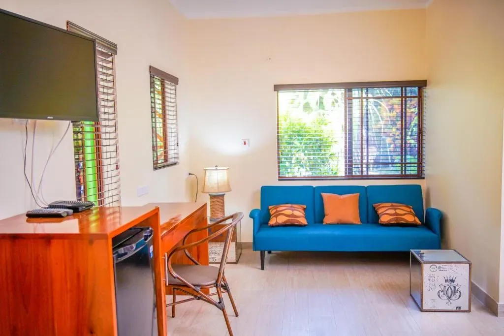 Sala de estar de la suite con sofá verde azulado y escritorio.