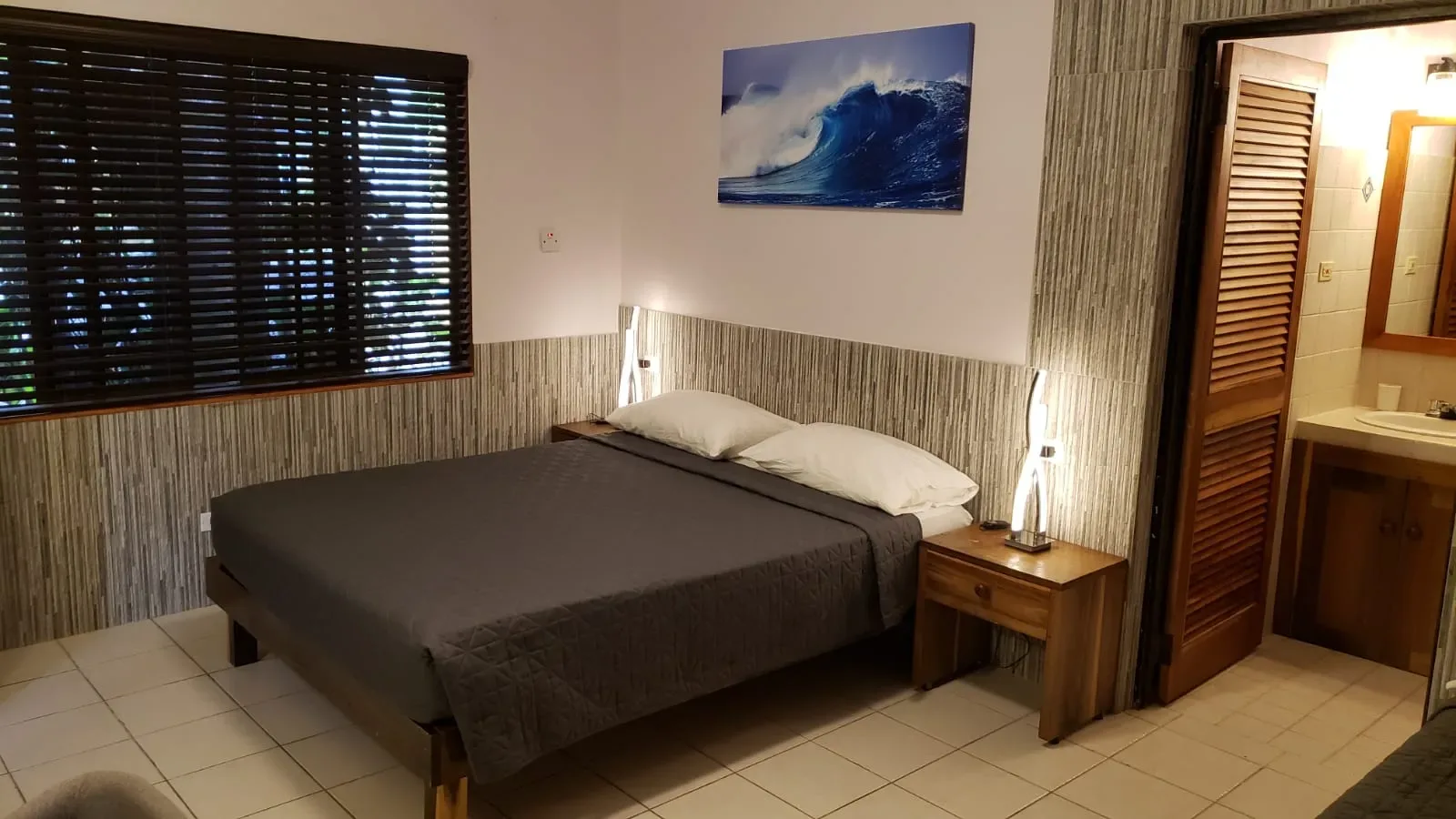 Dormitorio de Ocean Mist con cama, ventana y una obra de arte con olas.