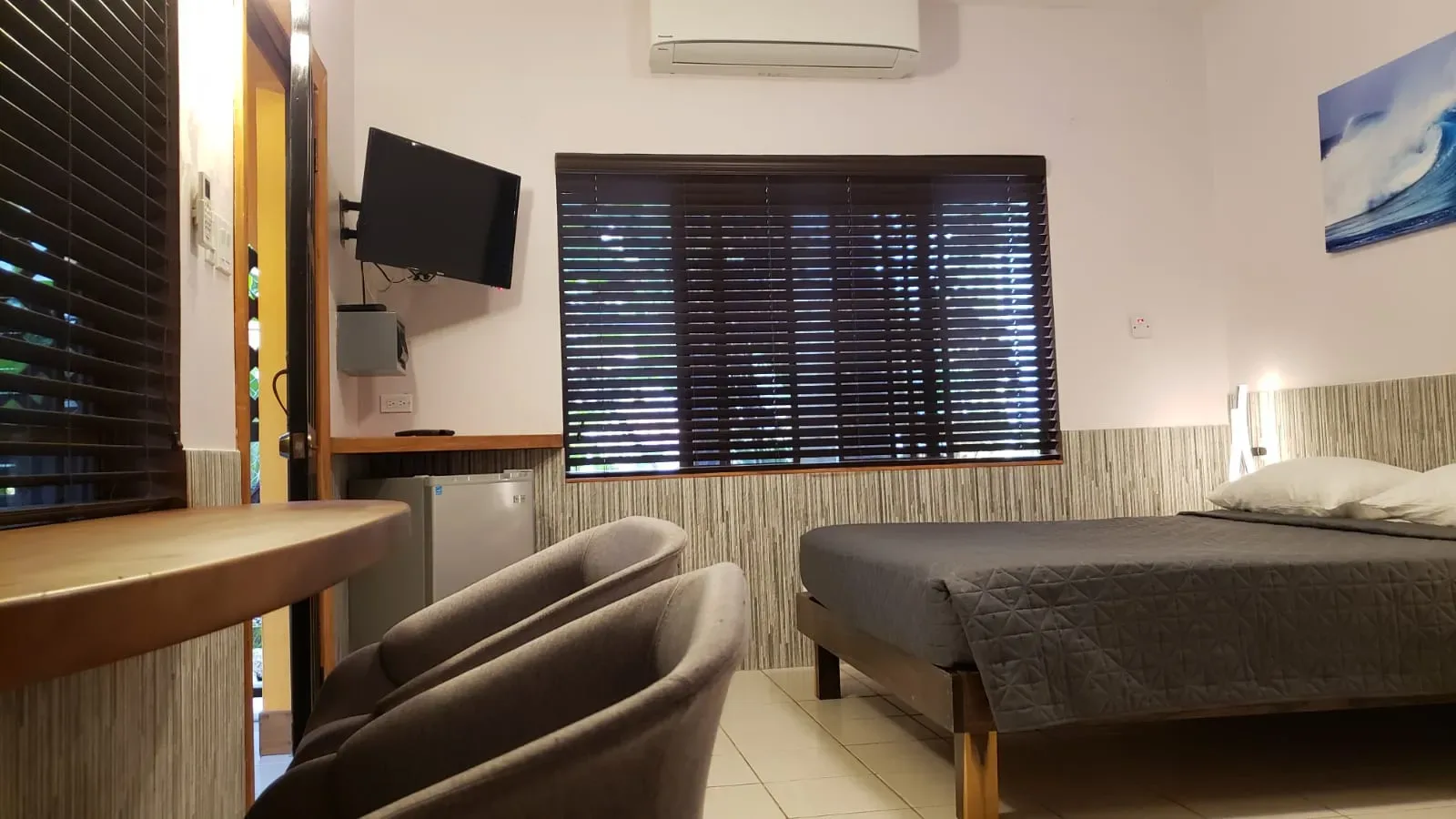 Dormitorio de Ocean Mist con cama, sillas, televisor y aire acondicionado.